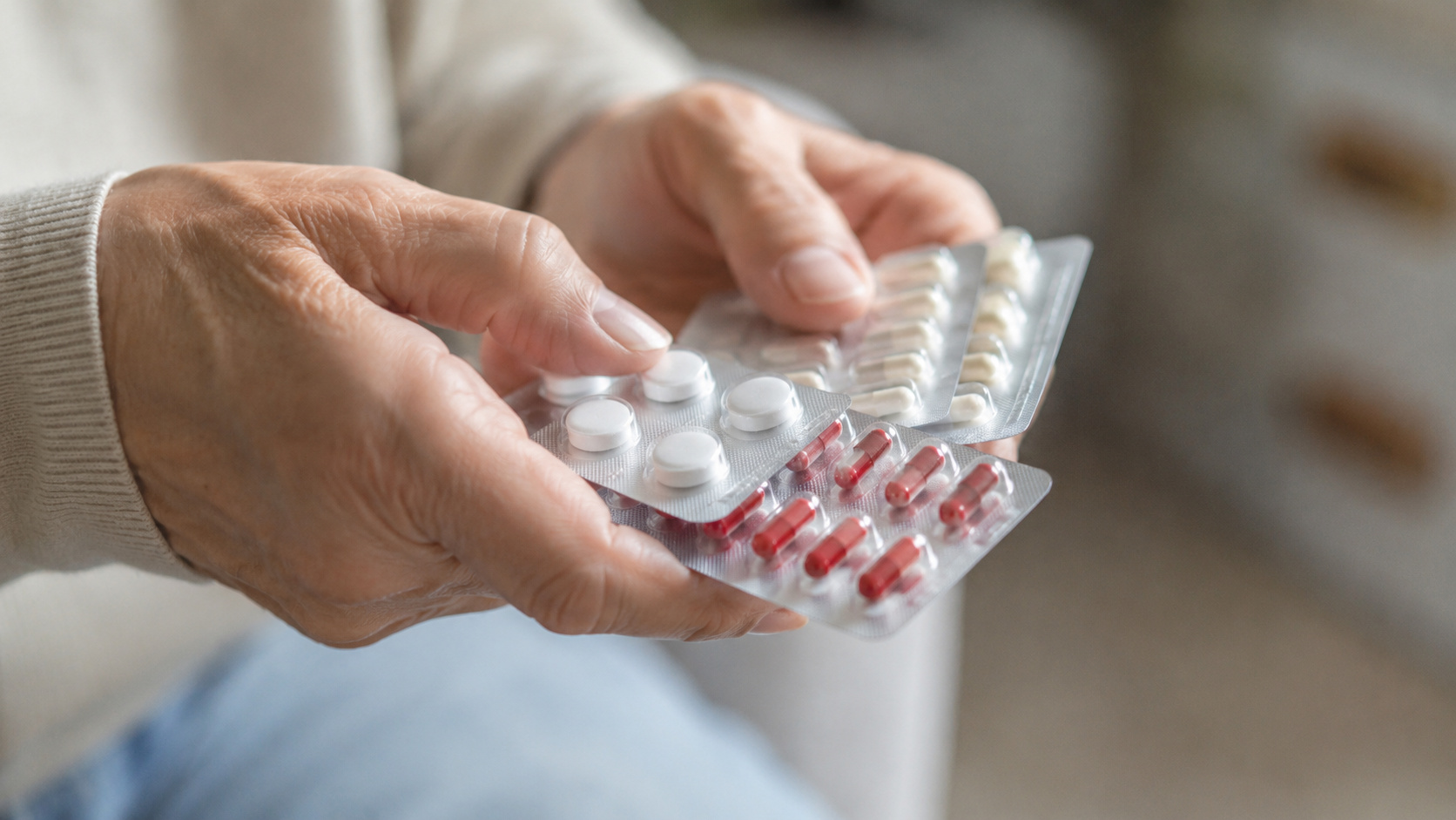 Mãos segurando cartelas de medicamentos em imagem ilustrativa sobre recolhimento de lotes e alerta da Anvisa