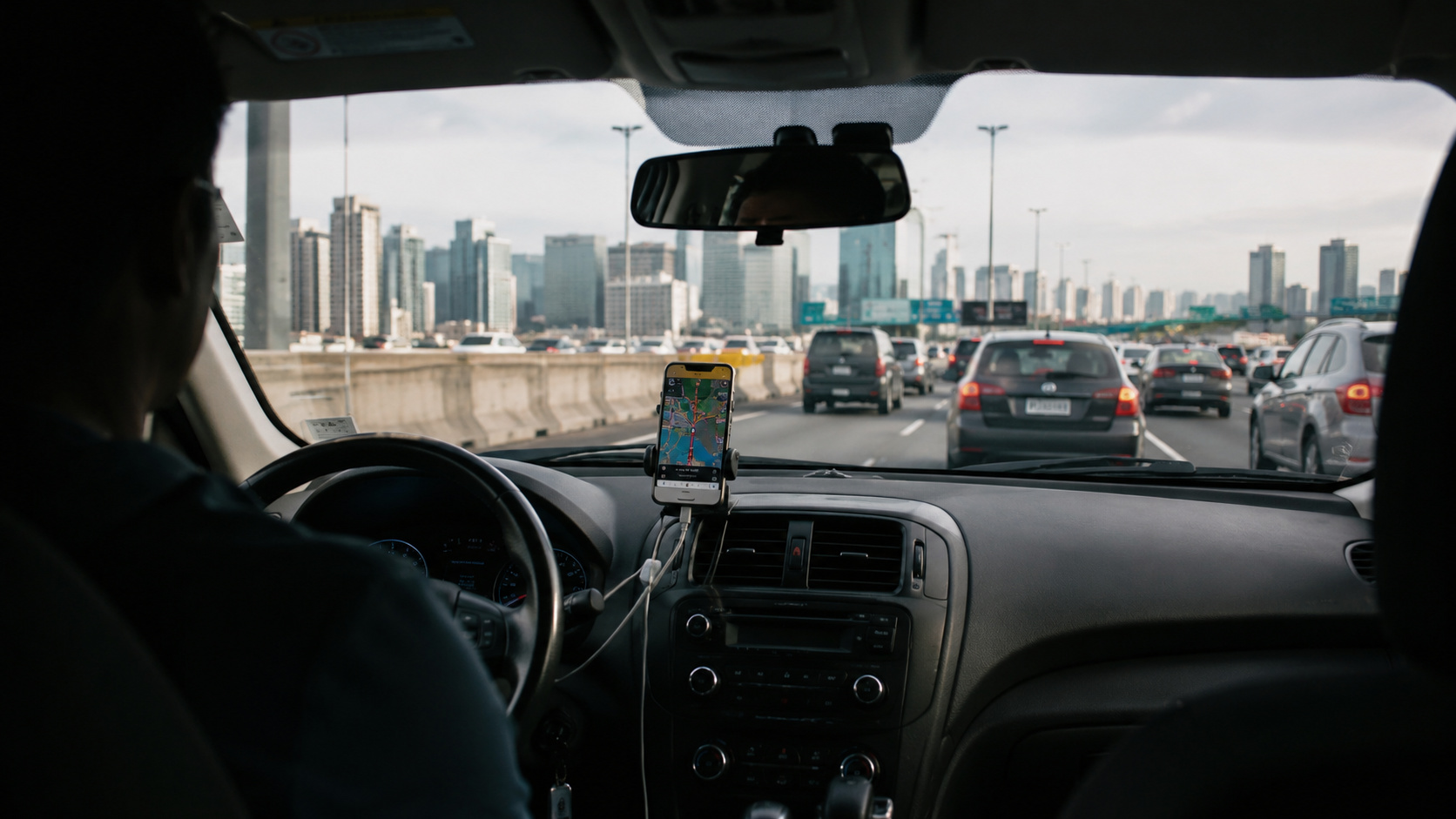 Motorista em carro de aplicativo dirige em meio ao trânsito urbano com celular exibindo rota de navegação no painel