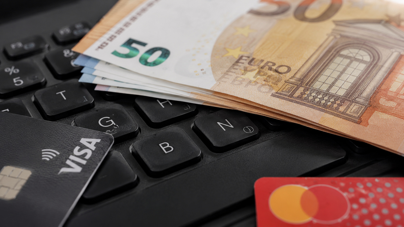 Notas de euro e cartões Visa e Mastercard sobre teclado representam o avanço do euro digital e dos pagamentos eletrônicos na Europa.