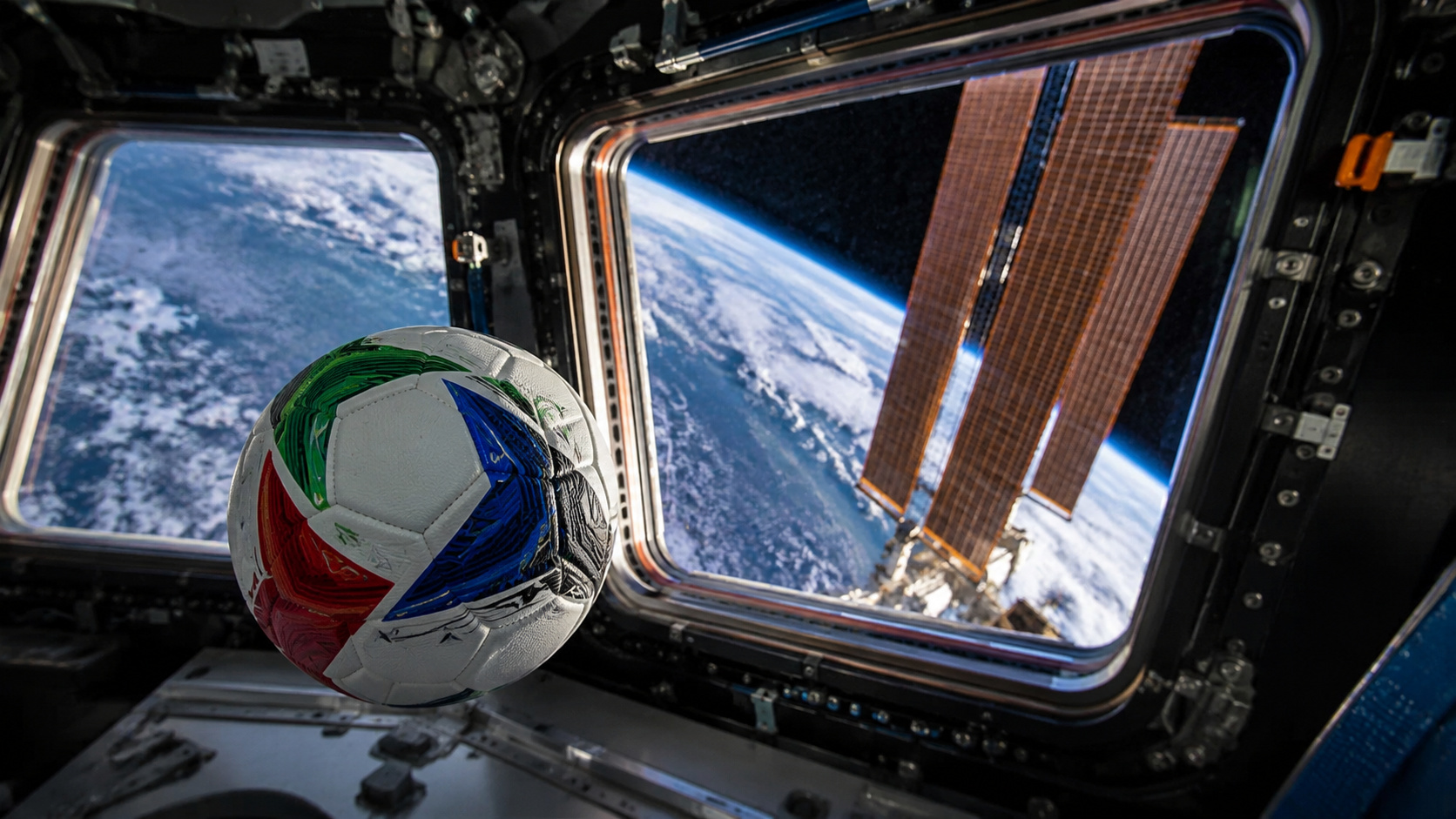 Bola de futebol flutuando em ambiente de microgravidade na Estação Espacial Internacional, com a Terra e painéis solares ao fundo