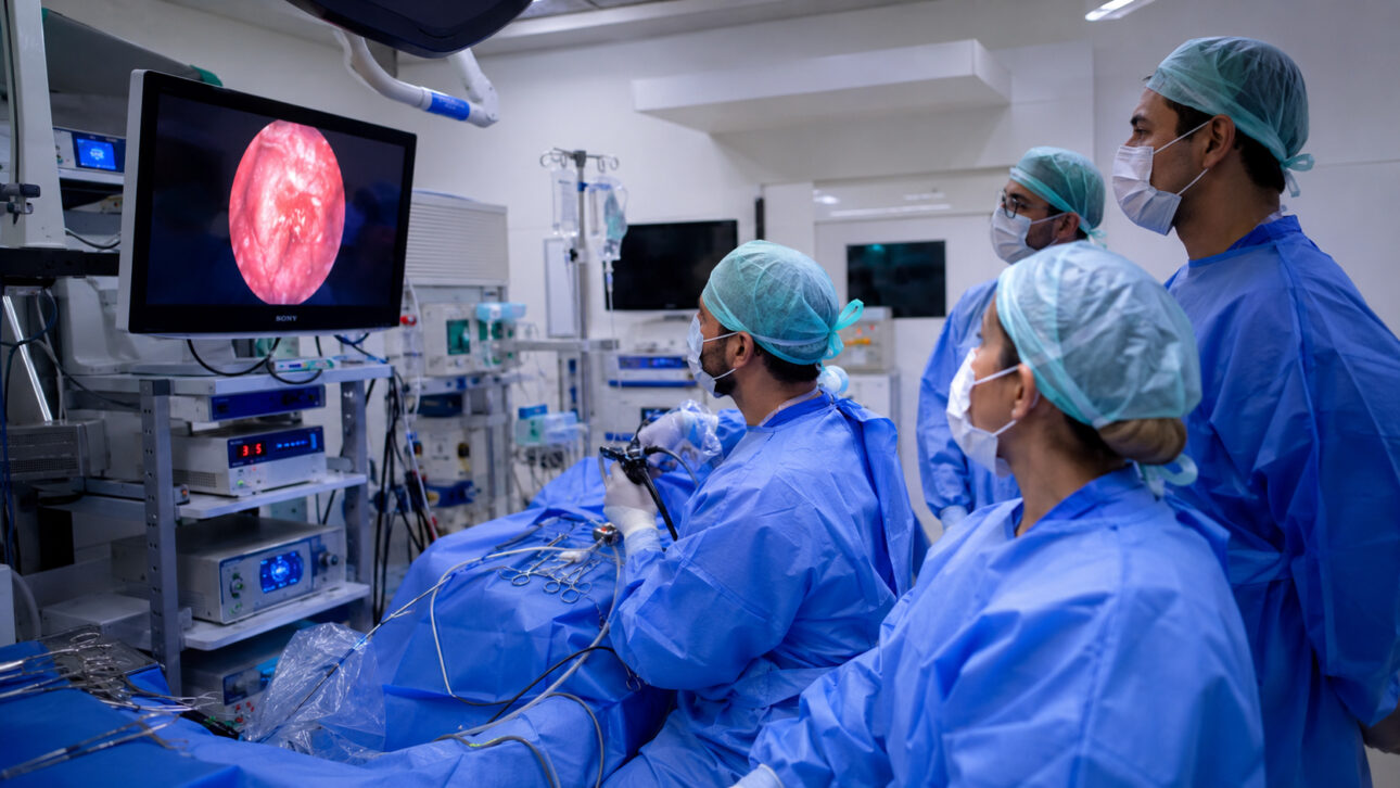 Surgeons observe monitor during endoscopic procedure to remove tumor from the pituitary gland.