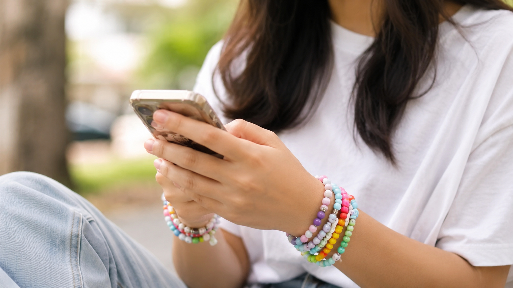 Adolescente usando smartphone em ambiente externo, imagem ilustrativa sobre proteção de crianças e adolescentes nas redes sociais nos EUA.