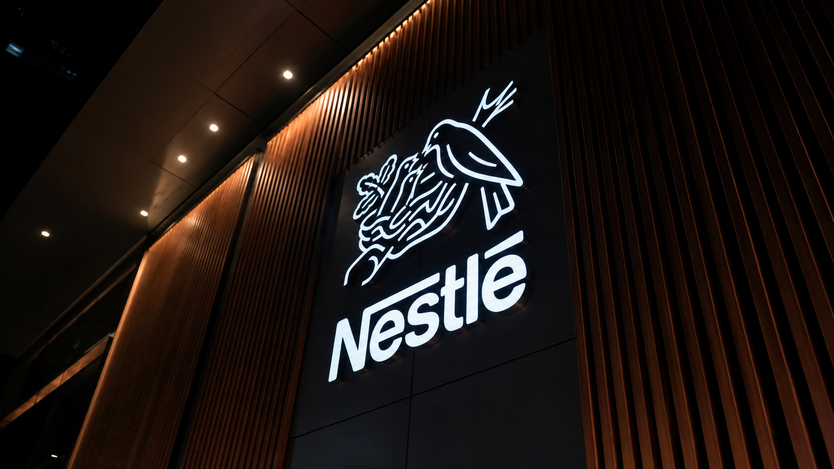 Logotipo iluminado da Nestlé em ambiente corporativo moderno, destacando a identidade visual da empresa durante anúncio da aquisição da yfood Labs na Europa.