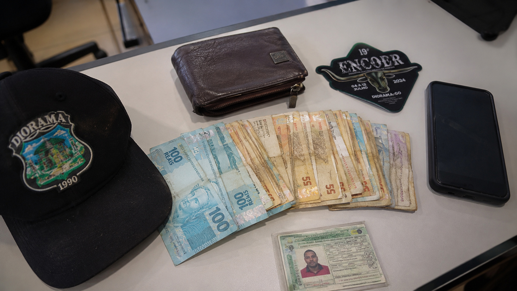 Servidor público exibe itens recuperados após encontrar carteira com dinheiro, documentos pessoais e objetos pertencentes a trabalhador rural em Diorama, Goiás.
