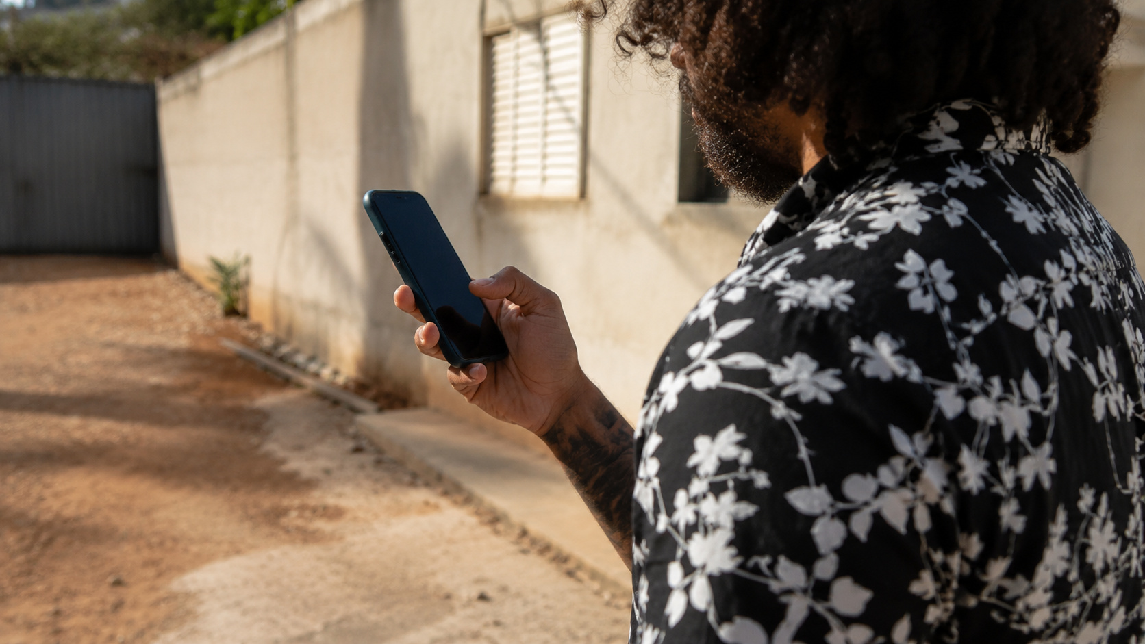 Homem utilizando um smartphone em área externa enquanto consulta uma ligação, ilustrando os novos recursos do Android para identificar chamadas falsas feitas com inteligência artificial.