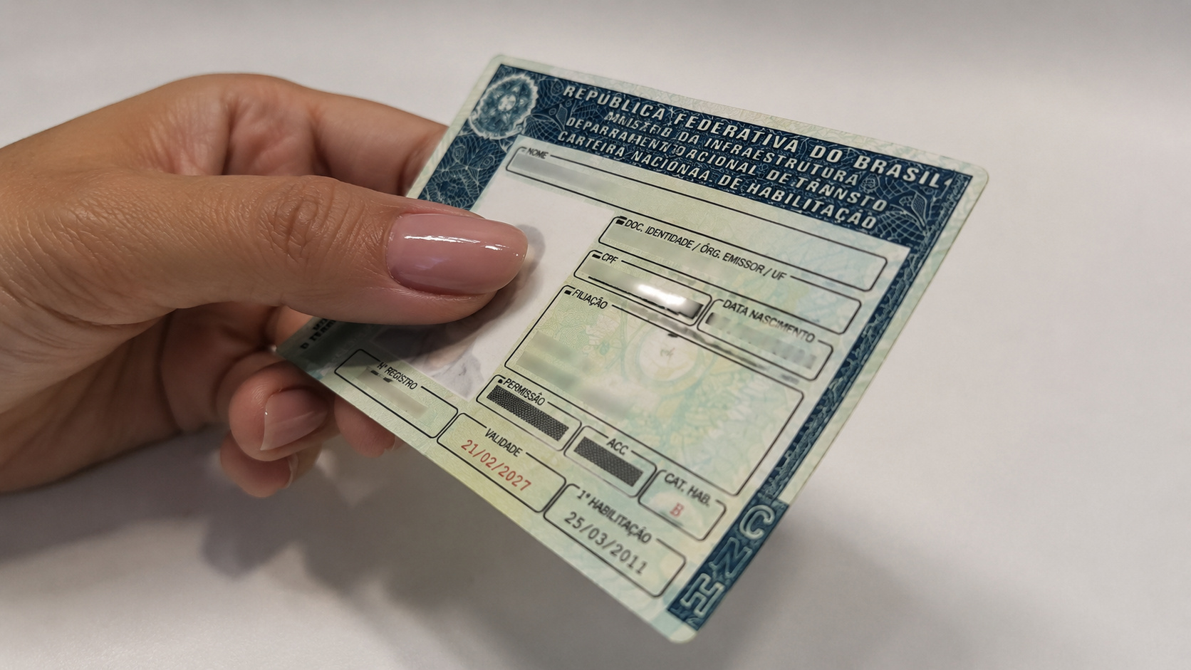 Pessoa segurando uma Carteira Nacional de Habilitação (CNH) durante processo de renovação, tema relacionado à revisão de benefícios por incapacidade do INSS.