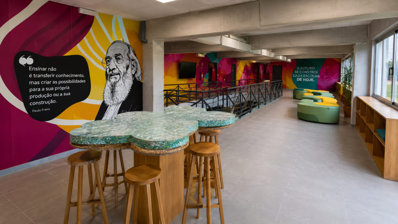 Internal area of the School of the Future with tables made from recycled materials, colorful educational murals, modern social space, sustainable furniture, and an environment focused on innovative teaching and environmental education.