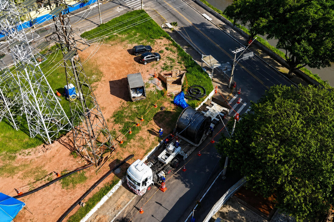 Equipe realiza instalação de cabos subterrâneos de transmissão de energia ao lado de torres elétricas em área urbana de São Paulo, durante a execução do Projeto Riacho Grande.