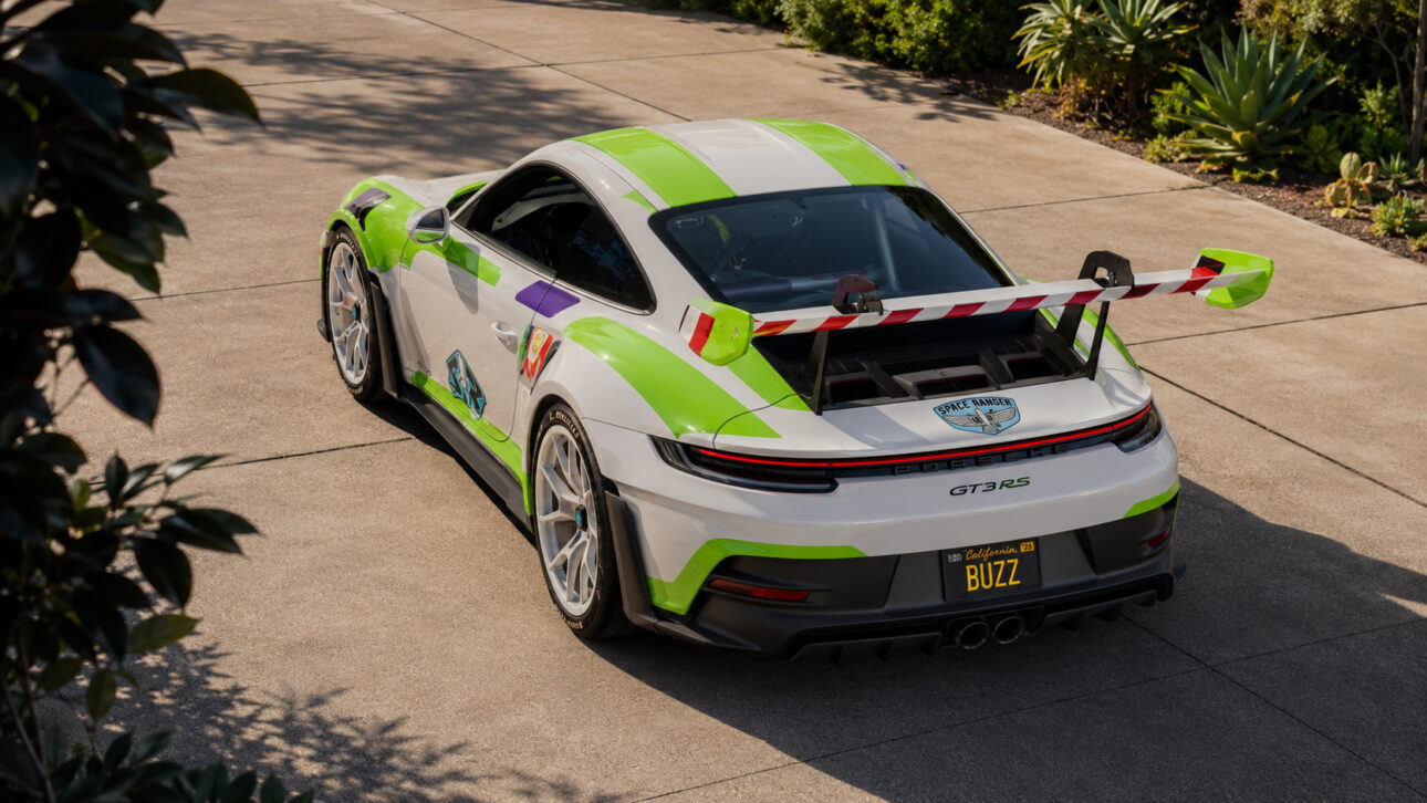 Porsche 911 GT3 RS personalizado com visual inspirado em Buzz Lightyear, nas cores branco, verde e roxo, fotografado em perspectiva elevada em uma área externa cercada por vegetação ornamental.