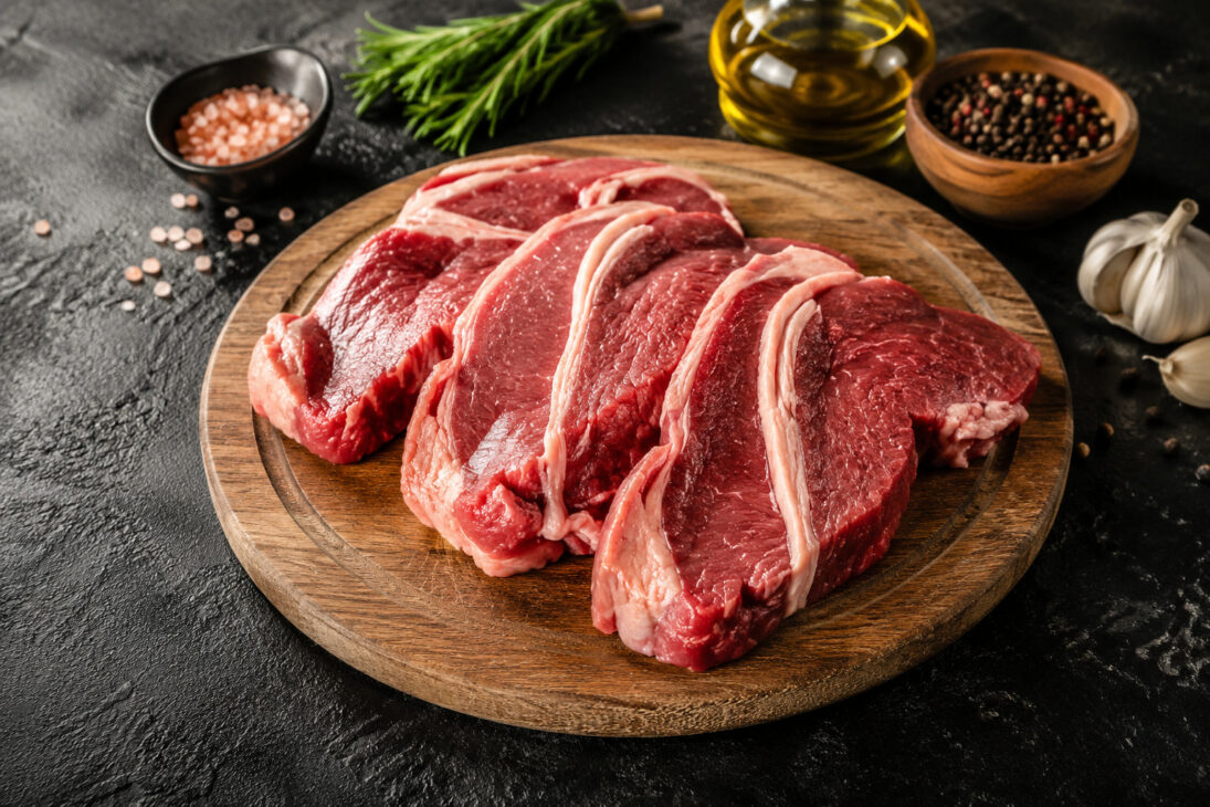Beef brisket tips arranged on a wooden board, accompanied by garlic, herbs, salt, and olive oil, illustrating the meat that has gained popularity among Brazilians for its juiciness and versatility in preparation.