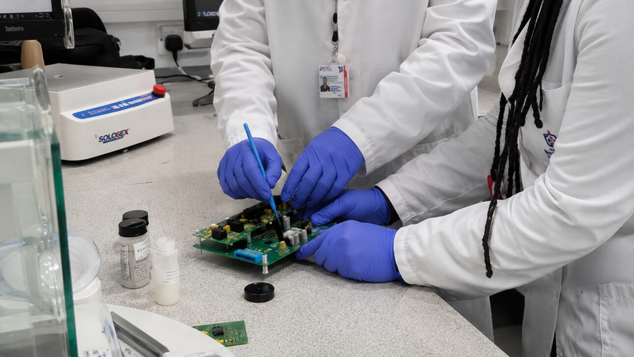 Pesquisadores realizam testes em uma placa eletrônica utilizando tecnologia de cola condutora reversível desenvolvida para substituir a solda tradicional e facilitar a reciclagem de componentes.