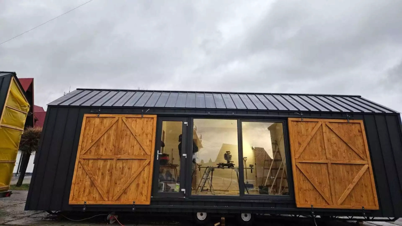 35 m² modular house on wheels bets on a wide glass facade, wooden doors, and a ground floor plan to try to transform a compact dwelling into a permanent house with an apartment appearance.