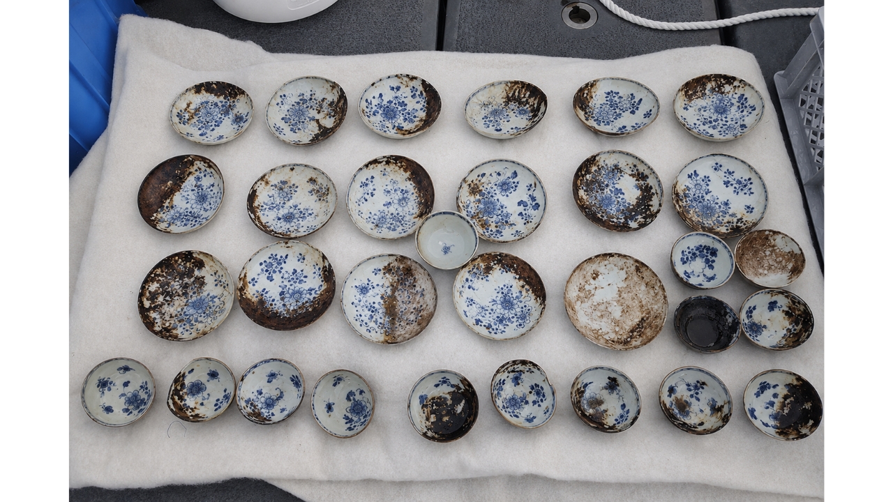Chinese porcelains recovered from the shipwreck found at 600 meters deep in the Skagerrak, Norway, reveal how 18th-century plates and bowls remained preserved for almost 300 years at the bottom of the sea, alongside goblets, fabrics, grains, and parts of chandeliers that still challenge archaeologists about the ship's origin and destination.