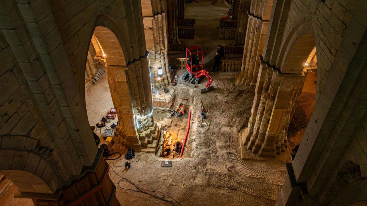 Arqueólogos del INRAP excavan hasta tres metros de profundidad en el interior de la Iglesia de Saint-Philibert, en Dijon. La escalera iluminada al fondo llevaba a la cripta sellada por 400 años — Crédito: Christophe Fouquin / INRAP