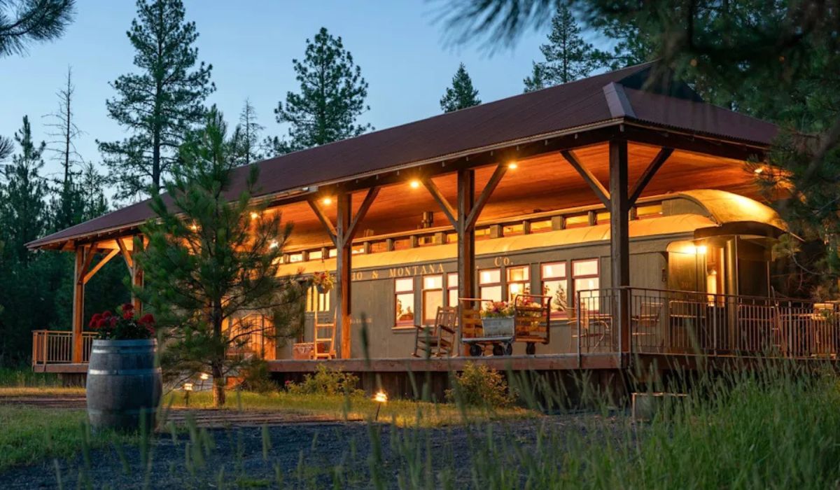The restored train carriage rests under a railway station-style cover, with a wide porch. Isaac French