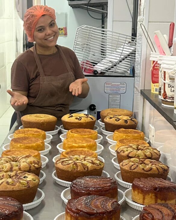 Jéssica Cristina Soares Fernandes, fundadora da Cacau Love, posa em meio aos bolos produzidos pela marca no Guarujá, negócio que nasceu dentro de casa e cresceu até ganhar fábrica, loja, delivery e faturamento próximo de R$ 2 milhões.