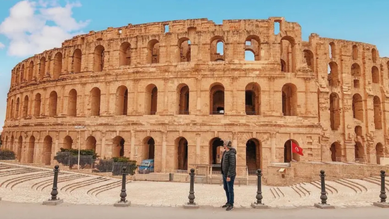Anderson Dias posa em frente ao Anfiteatro de El Jem, na Tunísia, durante sua volta ao mundo em 2019. Foto: acervo pessoal