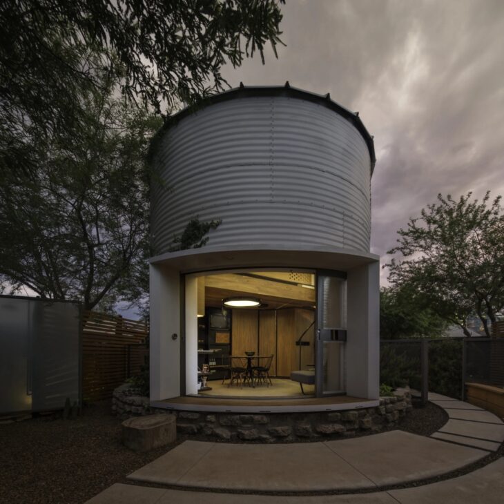 Con puerta curva abierta hacia el jardín, la Silo House revela el interior planeado por Christoph Kaiser, con carpintería de nogal, acero negro, sala integrada y soluciones hechas a medida para aprovechar la planta circular y reducir la sensación de poco espacio.