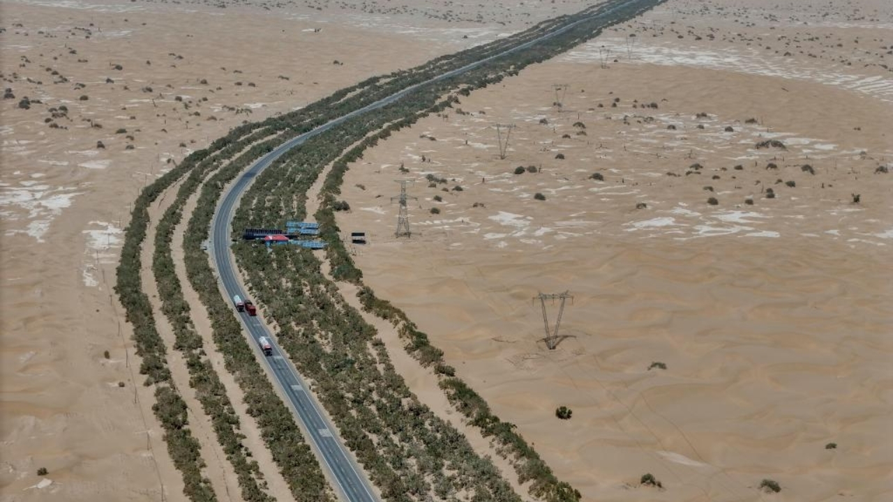 Foto aérea feita por drone em 18 de julho de 2025 mostra a Rodovia do Deserto de Tarim cortando o deserto de Taklamakan, na Região Autônoma Uigur de Xinjiang, no noroeste da China. Ao longo da estrada, é possível ver o cinturão verde plantado para conter o avanço da areia. A rodovia tem 522 km de extensão e atravessa o Taklamakan, considerado o segundo maior deserto de areia móvel do mundo. (Foto: Xinhua)