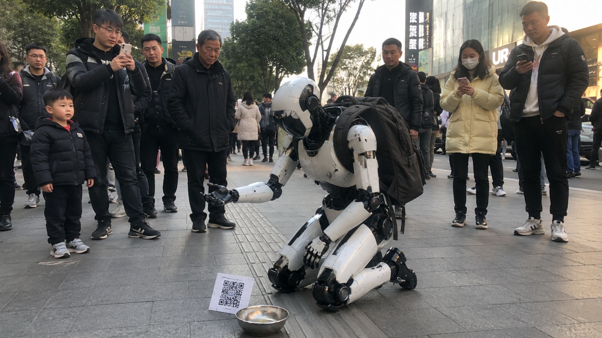 Robô humanoide ajoelhado com tigela e QR Code viraliza na China em vídeo curioso, mas cena ainda não tem confirmação oficial.