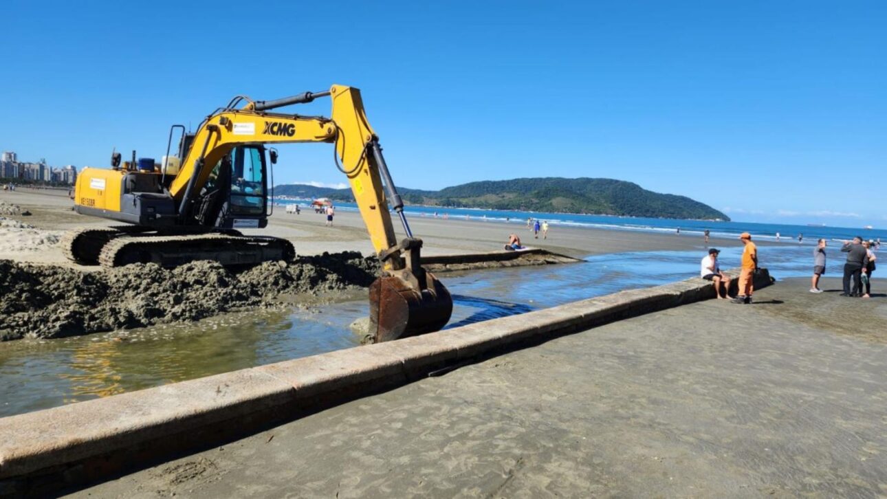 Canal em Santos fica assoreado após ressaca, com areia acumulada e escavadeira atuando na drenagem urbana. (Imagem: Divulgação/Prefeitura de Santos).