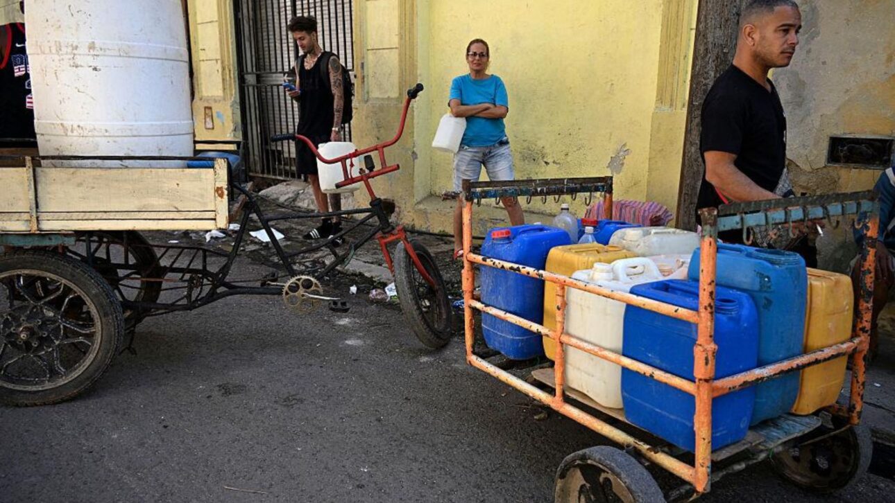 Moradores de Havana carregam galões de água durante apagão em Cuba, em meio à falta de energia e combustível. (Imagem: Getty Images)