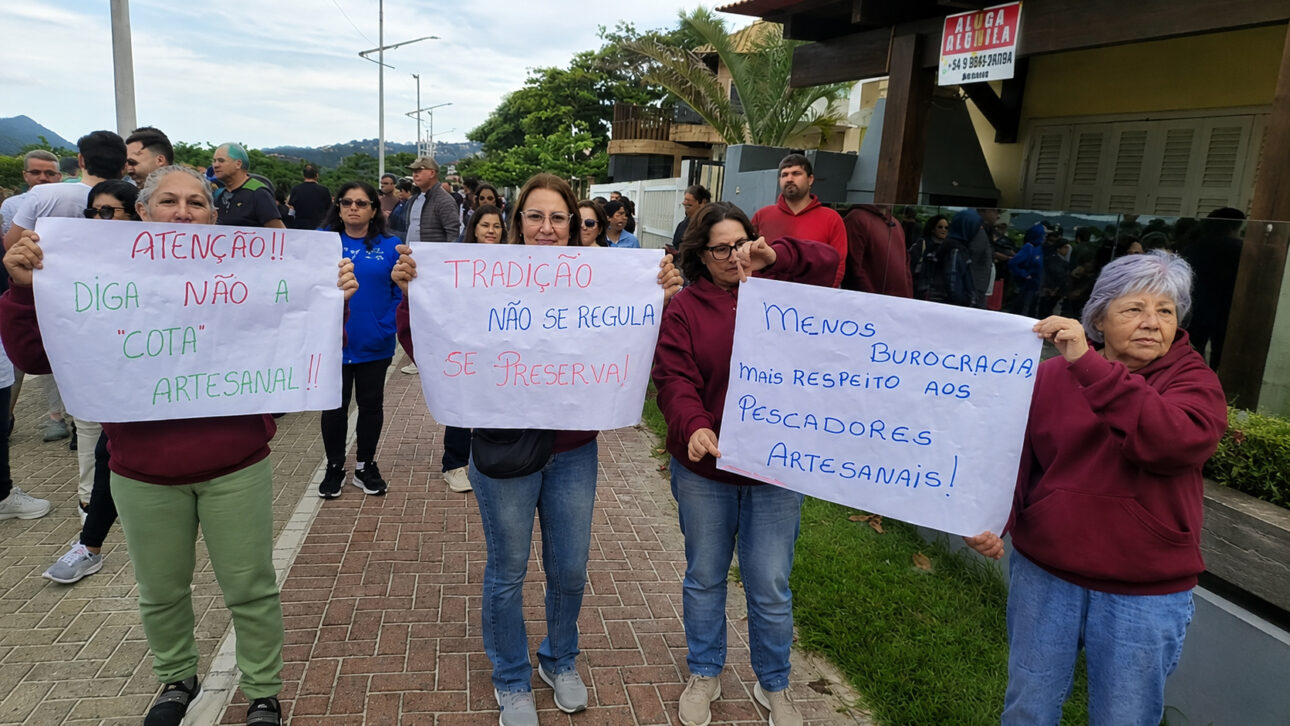 Grupo de manifestantes segura cartazes em apoio aos pescadores artesanais de Santa Catarina, cobrando menos burocracia e criticando cotas na pesca da tainha.