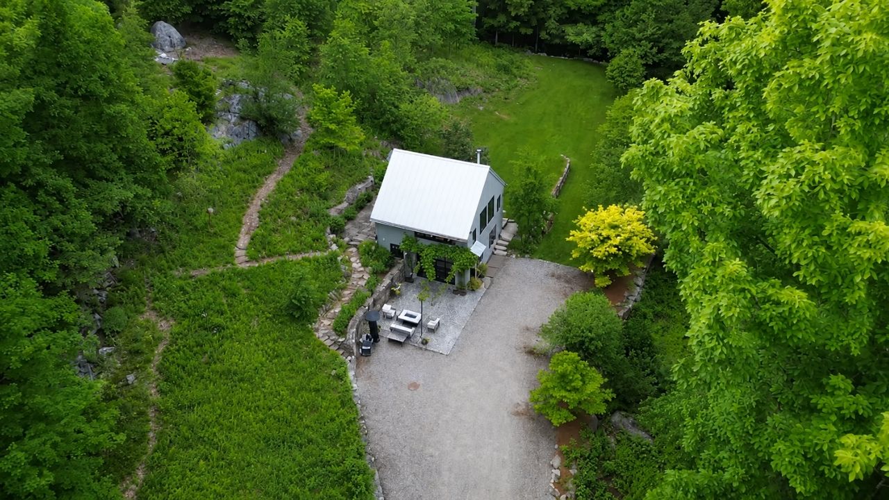 A mini casa em Connecticut nasceu de garagem e ganhou sauna, rio e móveis escondidos em refúgio compacto de 700 pés quadrados.