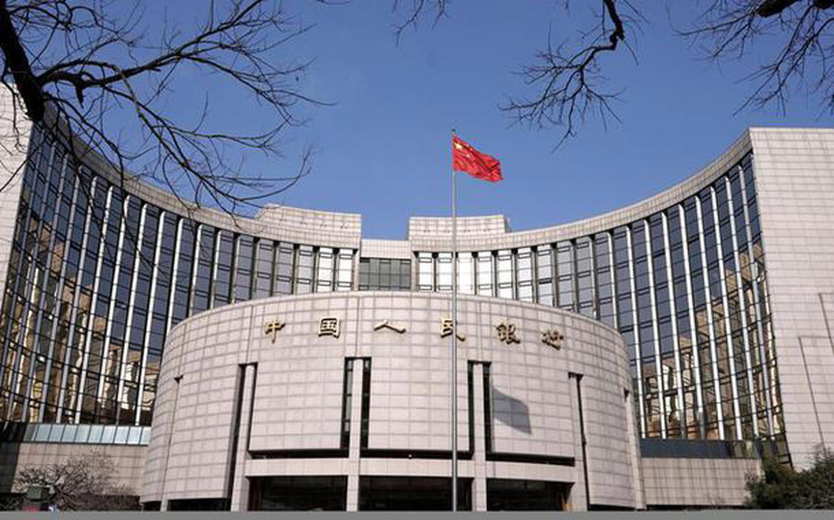 Fachada do Banco Popular da China com bandeira chinesa no topo, em referência ao avanço do mBridge e dos pagamentos digitais internacionais.
