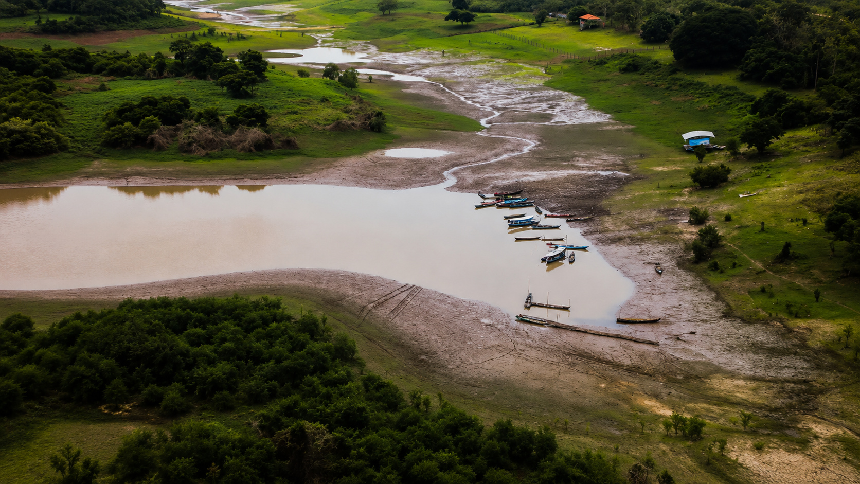 Vista aérea de área com baixo nível de água, margens expostas e embarcações encalhadas, ilustrando os impactos da redução das reservas hídricas e da pressão sobre a água subterrânea no Brasil.