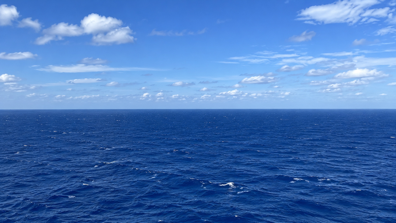 Oceano Atlântico aberto sob céu azul com nuvens, representando a corrente AMOC e os processos climáticos invisíveis nas profundezas.