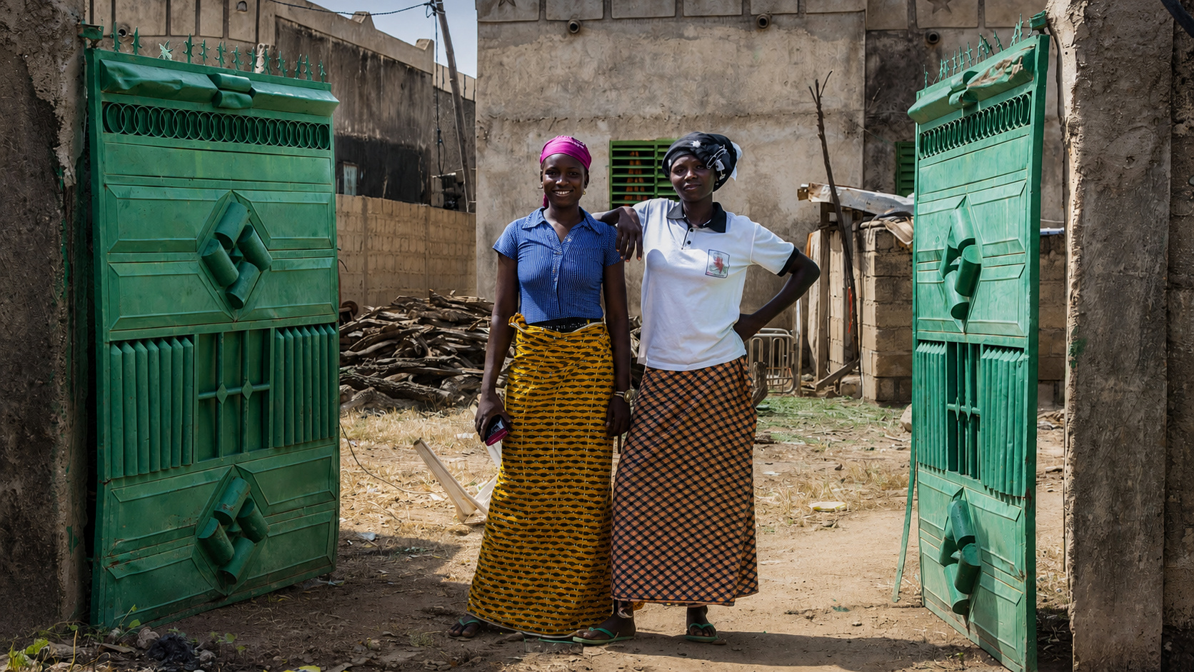 Mulheres de Beguédo posam em frente a uma residência no leste de Burquina Fasso, retratando a realidade das esposas que vivem anos longe dos maridos migrantes que trabalham na Europa.