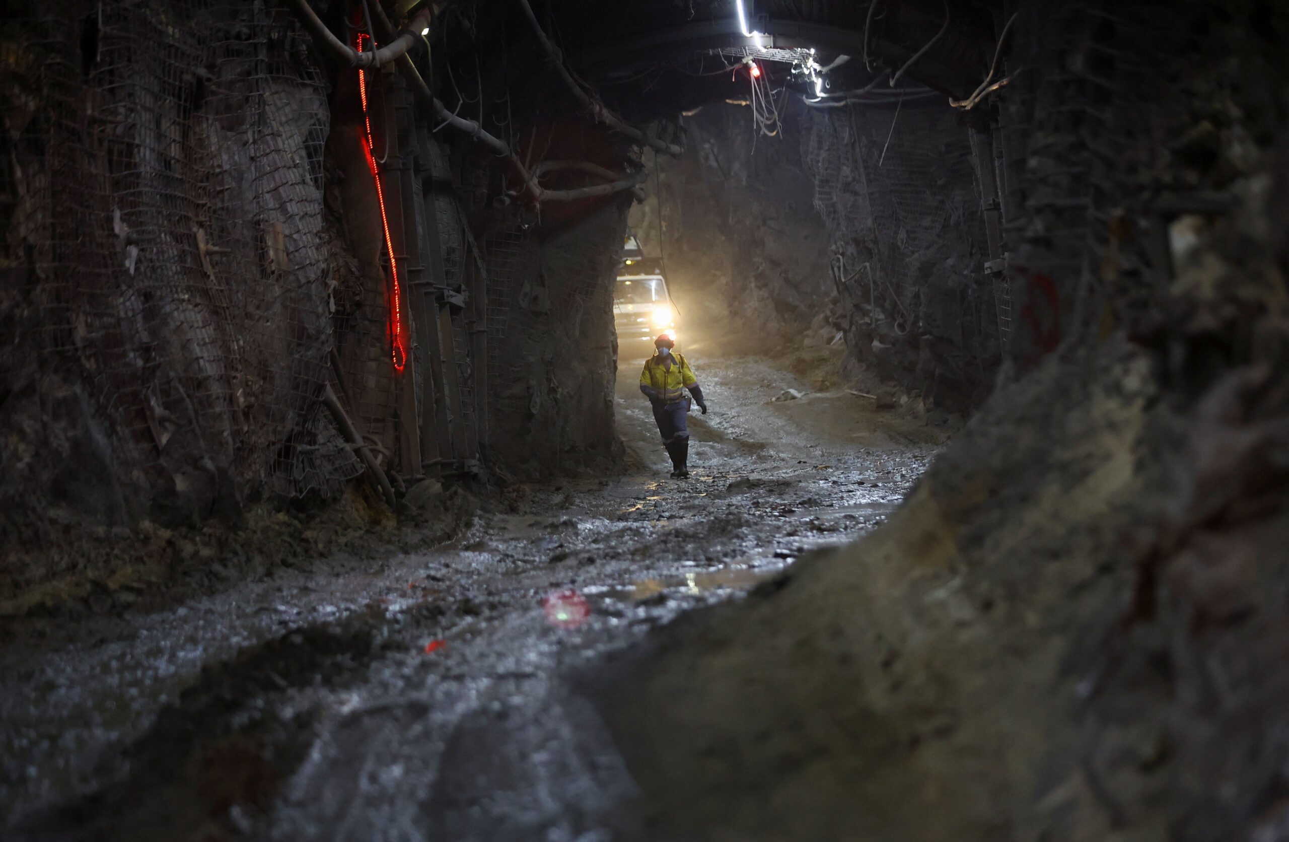 Túnel escuro de mina subterrânea profunda com trilhos
