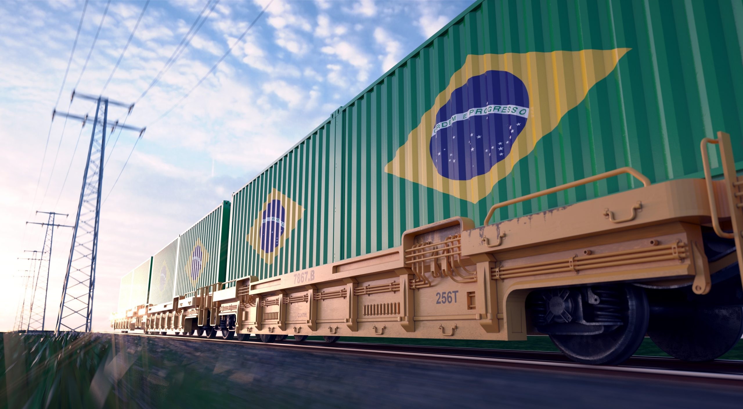 Trem de carga atravessando paisagem ao lado de rodovia