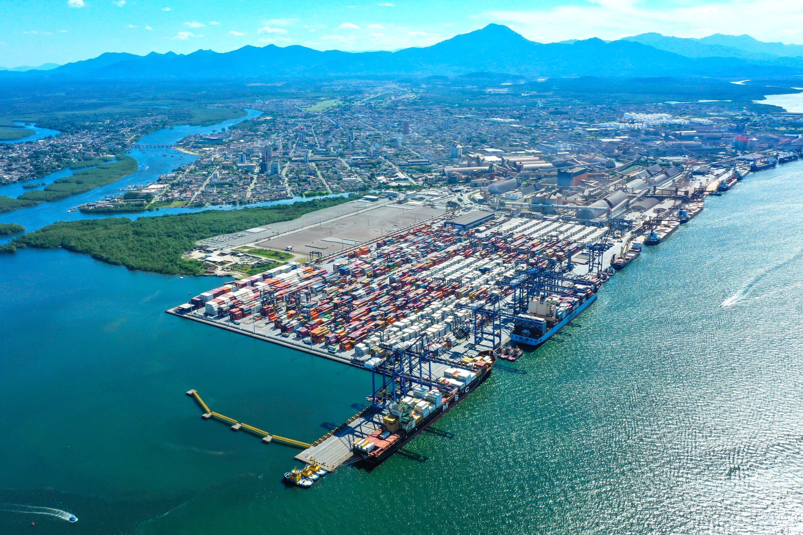 Vista aérea do Porto de Santos com navios e guindastes ao pôr do sol