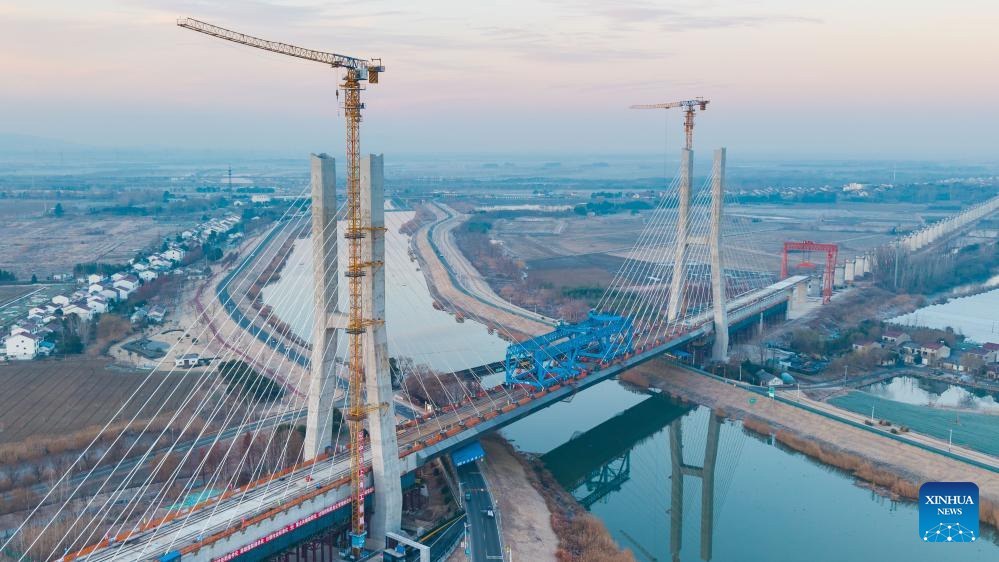 Construção de ponte com torres e guindastes