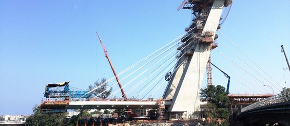 Construção de ponte sobre rio com guindastes