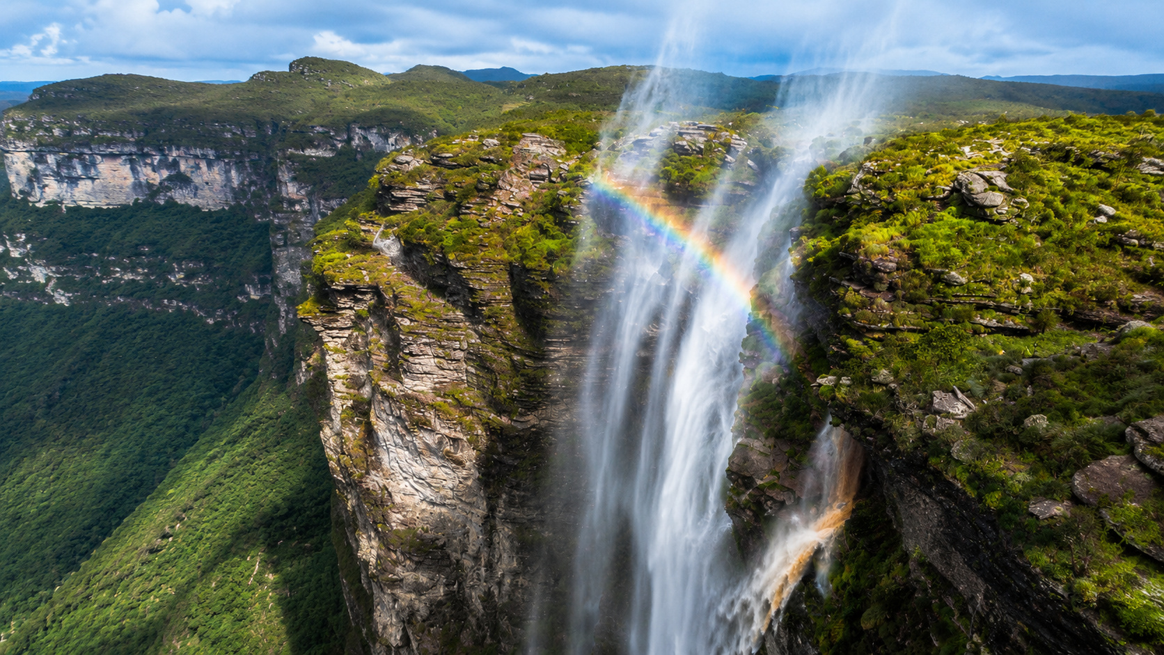 Cachoeira de grande altura em cânion rochoso com névoa sendo arrastada pelo vento, ilustrando o fenômeno natural que faz a água parecer subir em vez de cair.