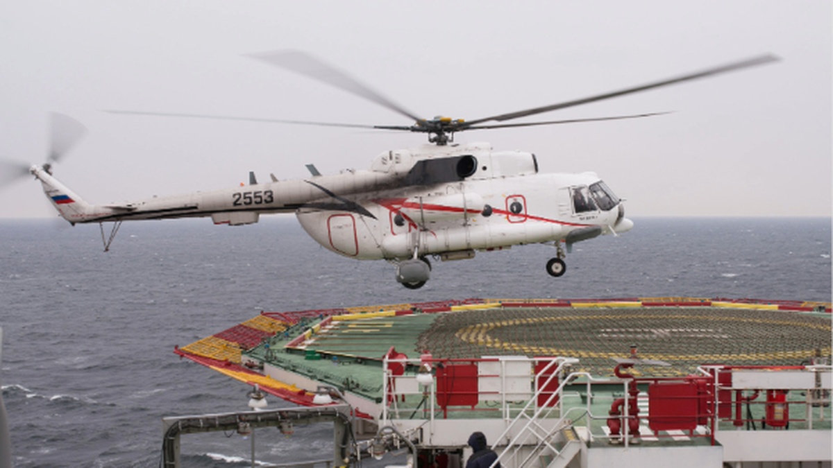 Helicóptero em operação offshore se aproxima de plataforma no mar, representando o transporte aéreo de trabalhadores do setor de petróleo e gás.