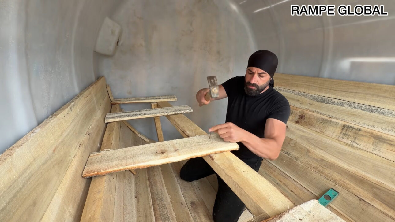 Repurposed water tank turns into a hobbit-style house with pallets, semi-buried structure, and curved facade in a project that combines recycling, low cost, and thermal insulation.