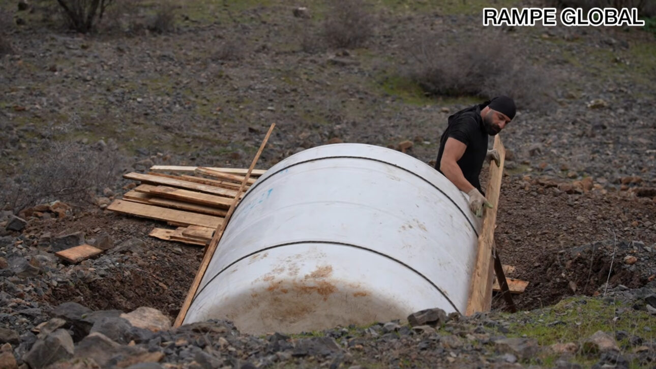 Reused water tank becomes a hobbit-style house with pallets, semi-buried structure, and curved facade in a project that combines recycling, low cost, and thermal insulation.