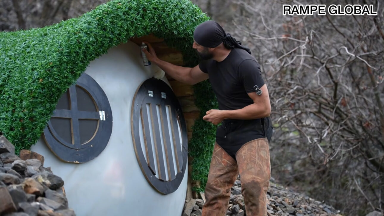 Repurposed water tank turns into a hobbit-style house with pallets, semi-buried structure, and curved facade in a project that combines recycling, low cost, and thermal insulation.