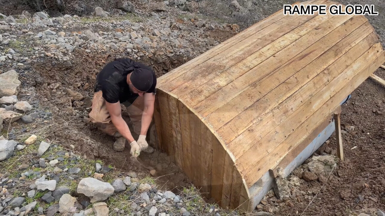 Reused water tank becomes a hobbit-style house with pallets, semi-buried structure, and curved facade in a project that combines recycling, low cost, and thermal insulation.