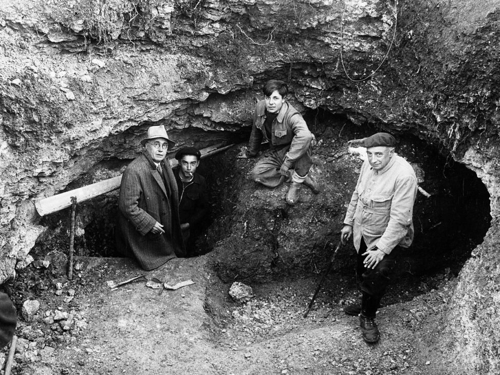 Four people in front of the entrance to the Lascaux Cave during the first works carried out at the French archaeological site.