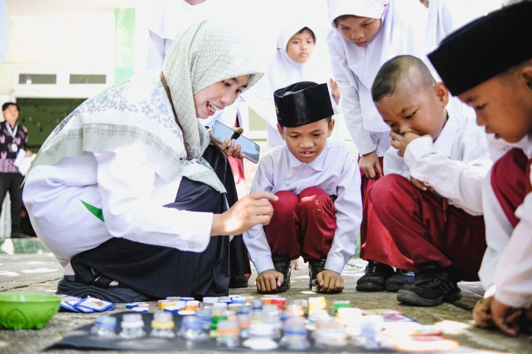 Teacher transforms bottle caps into letters, uses leaves, stones, and branches as class material and proves that literacy can emerge from recycled waste when resources are lacking in school