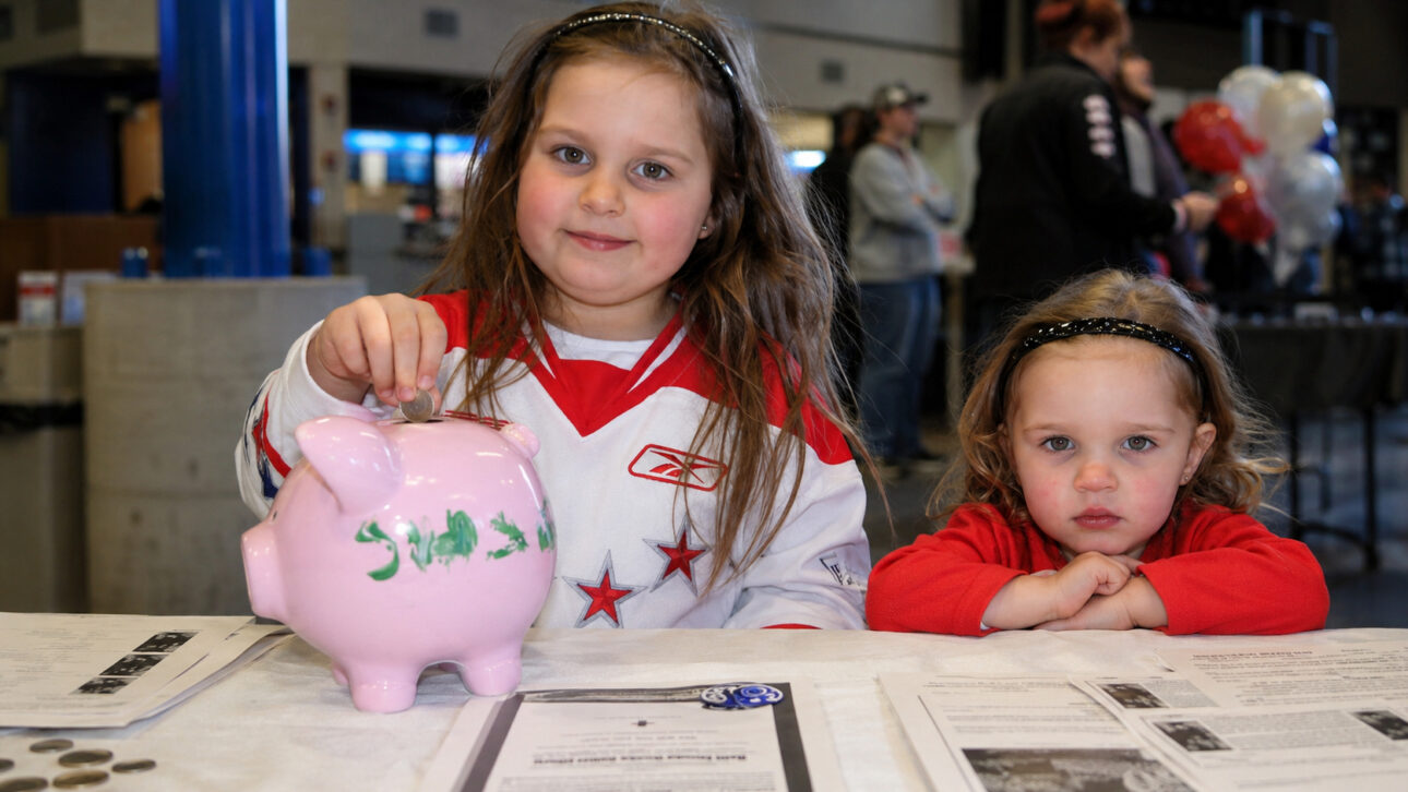 Dos niñas frente a una mesa de recaudación, con una alcancía rosa utilizada para reunir donaciones para las víctimas del terremoto en Haití.