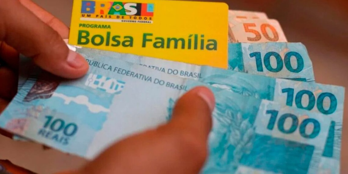 Cartão do Bolsa Família aparece junto a cédulas de real, simbolizando pagamento do benefício social.