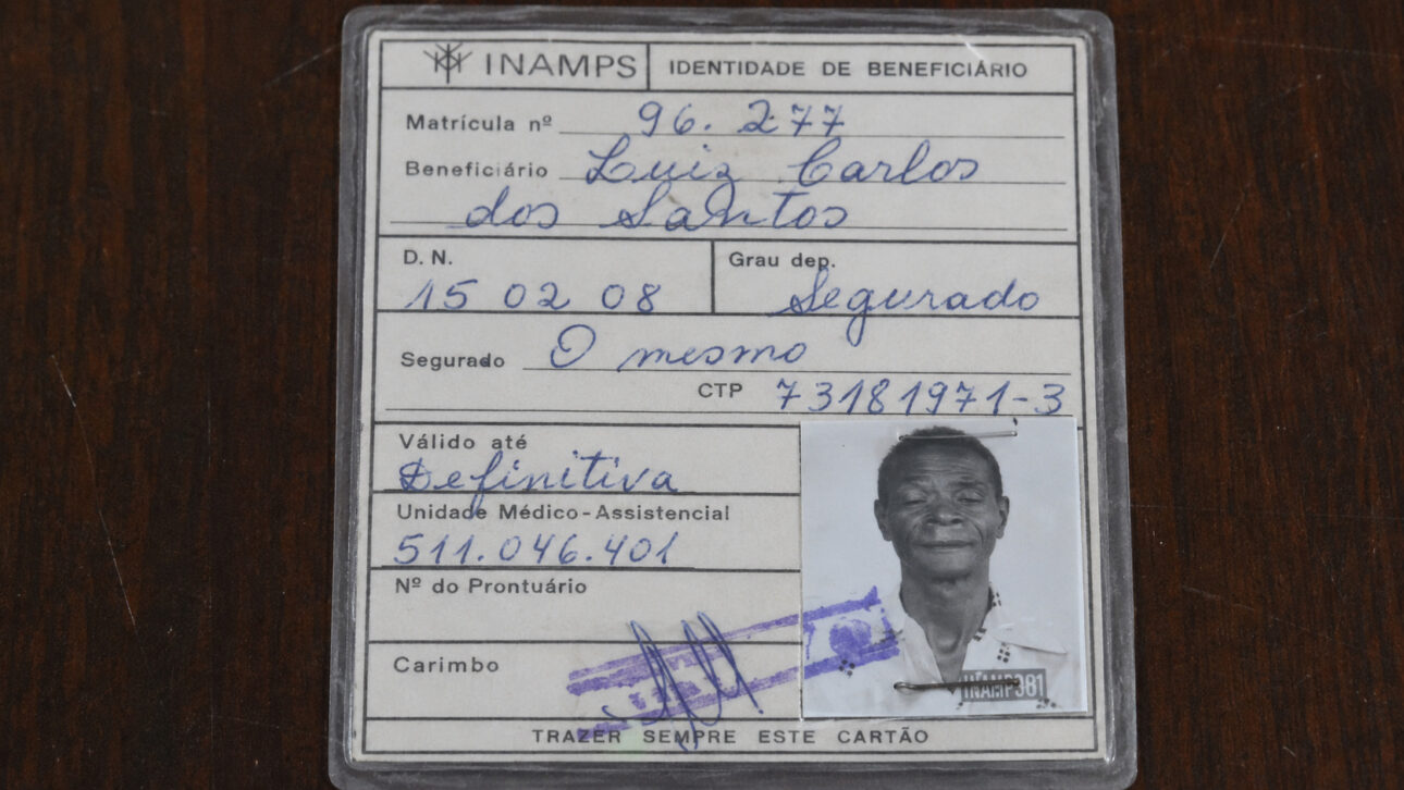 Carteira antiga do INAMPS com fotografia e dados de Luiz Carlos dos Santos, usada para comprovar sua identidade e data de nascimento.