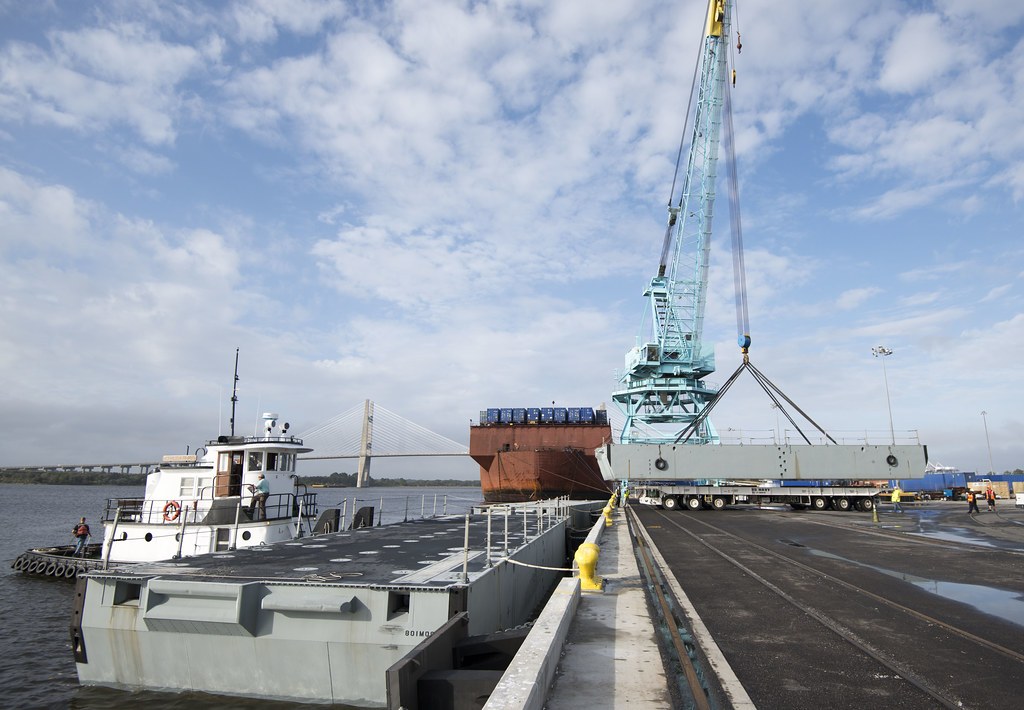 Crane loading giant industrial module onto vessel at port
