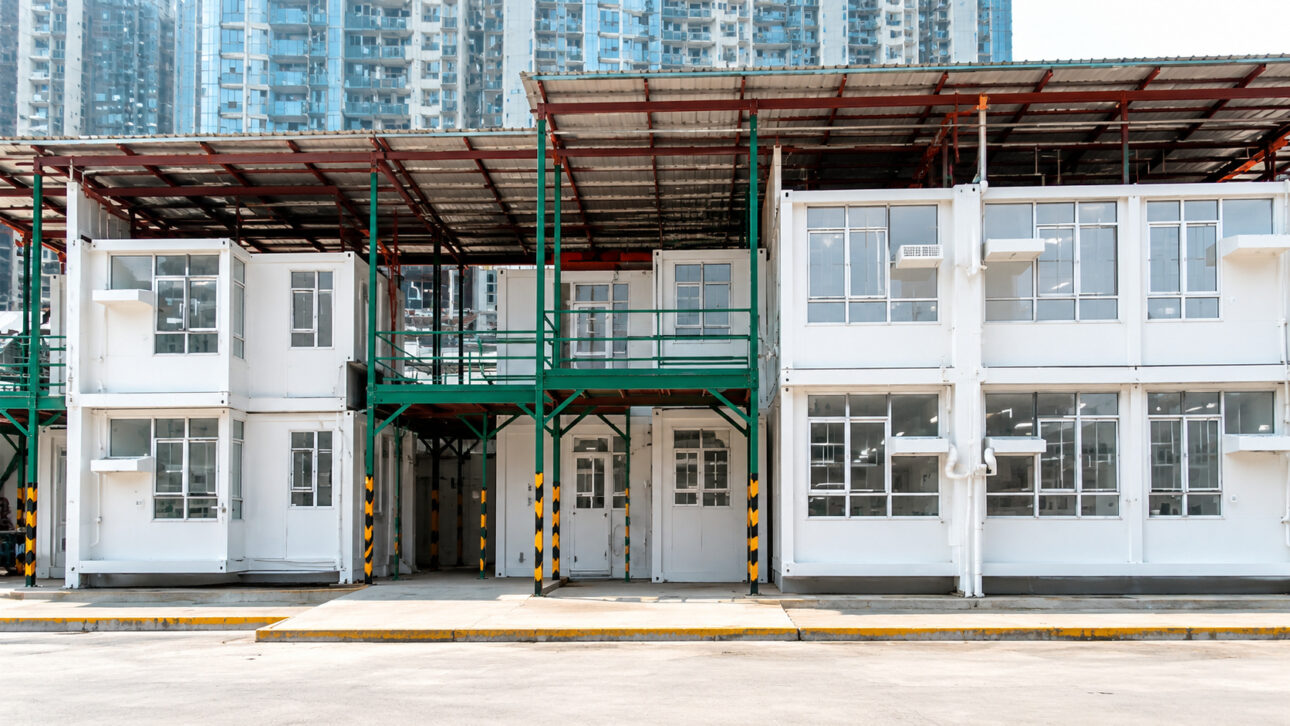 Illustrative image of trucks and cranes at a modular construction site